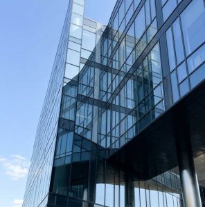 Arsitektur korporat modern berteknologi tinggi di bawah langit cerah yang merepresentasikan performa optimal dari layanan jasa web developer Sidoarjo.